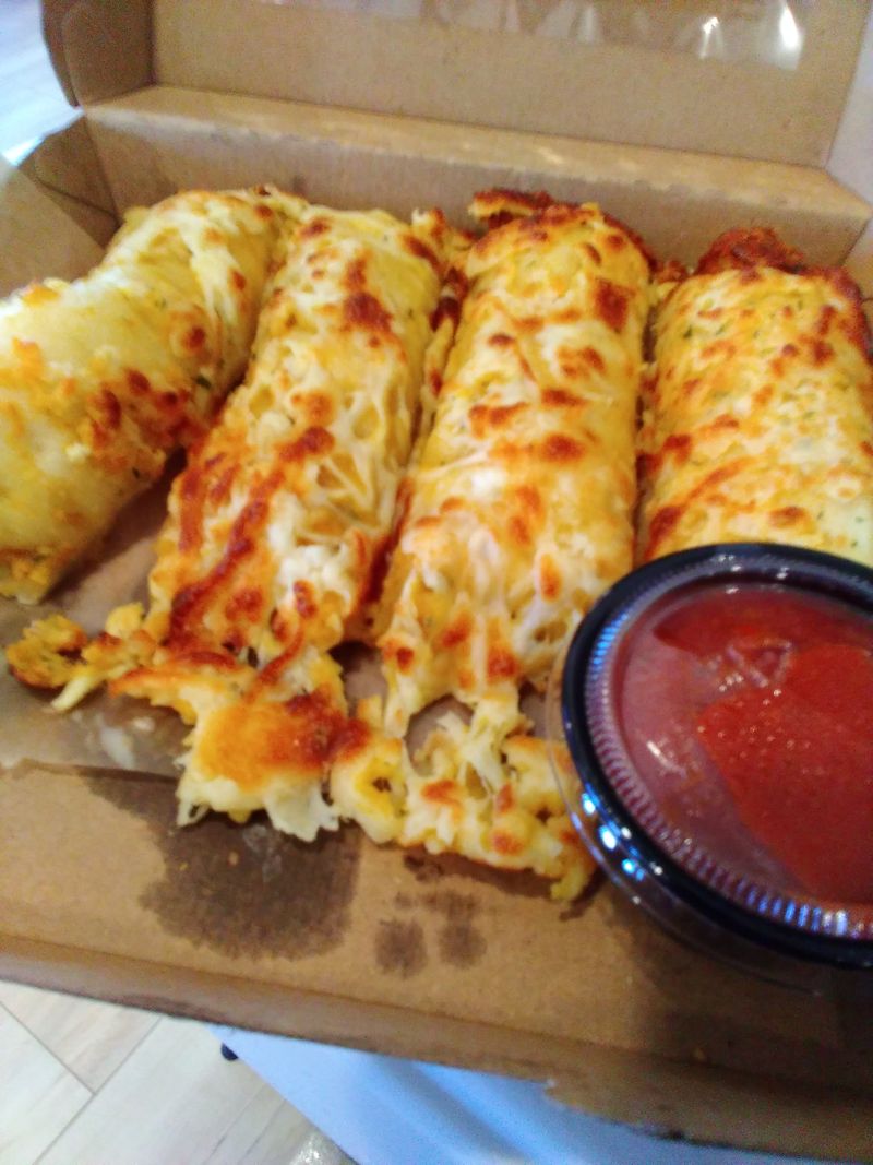 Photo of cheese breadsticks in a cardboard box.