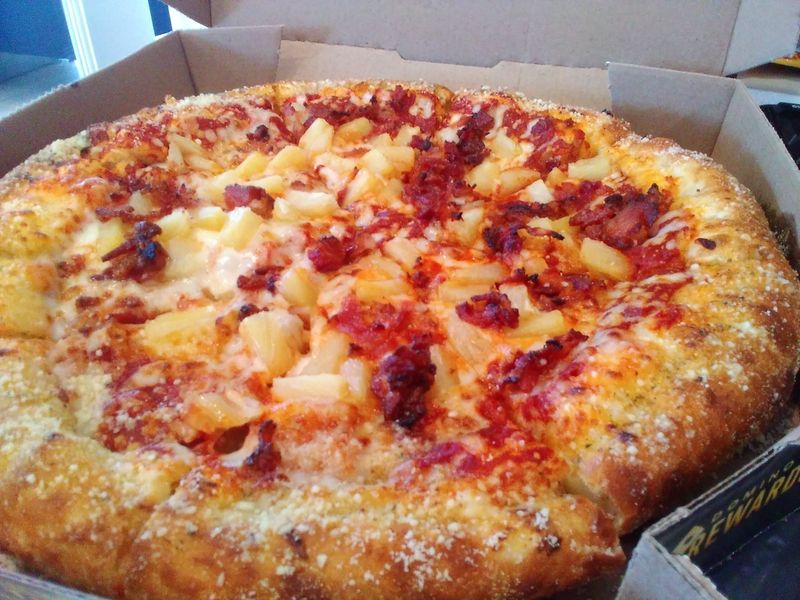 Photo of a bacon and pineapple stuffed-crust pizza in a pizza box.